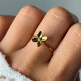 Bague en acier inoxydable doré, design fleur, portée sur un doigt. La fleur a quatre pétales et un centre texturé.
