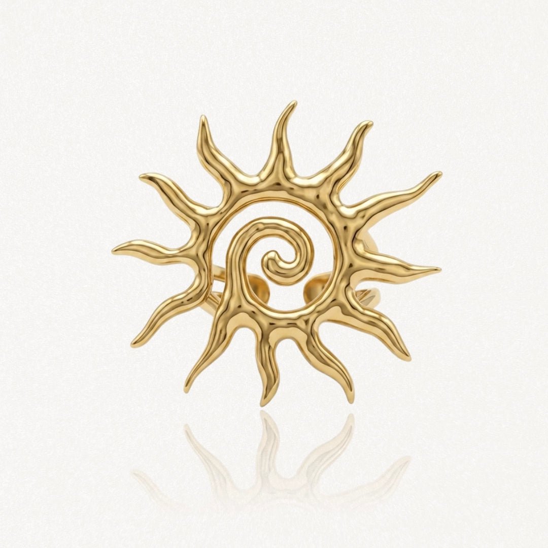 Bague ajustable en acier inoxydable doré, motif soleil stylisé avec spirale centrale.