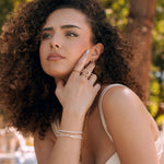Bague en acier inoxydable doré avec motif soleil spirale, portée par une femme aux cheveux bouclés.
