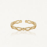 Bague ajustable en acier inoxydable doré, motif de billes et d'ovales ajourés.