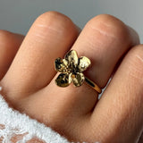 Bague fleur en acier inoxydable doré, de 1,50 cm, aux cinq pétales texturés et au cœur granuleux, portée sur un doigt.
