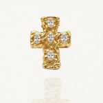 Bague dorée en forme de croix, présentant une surface texturée et organique. Cinq pierres ovales claires sont serties sur la croix. L'objet est photographié sur un fond blanc avec un léger reflet.