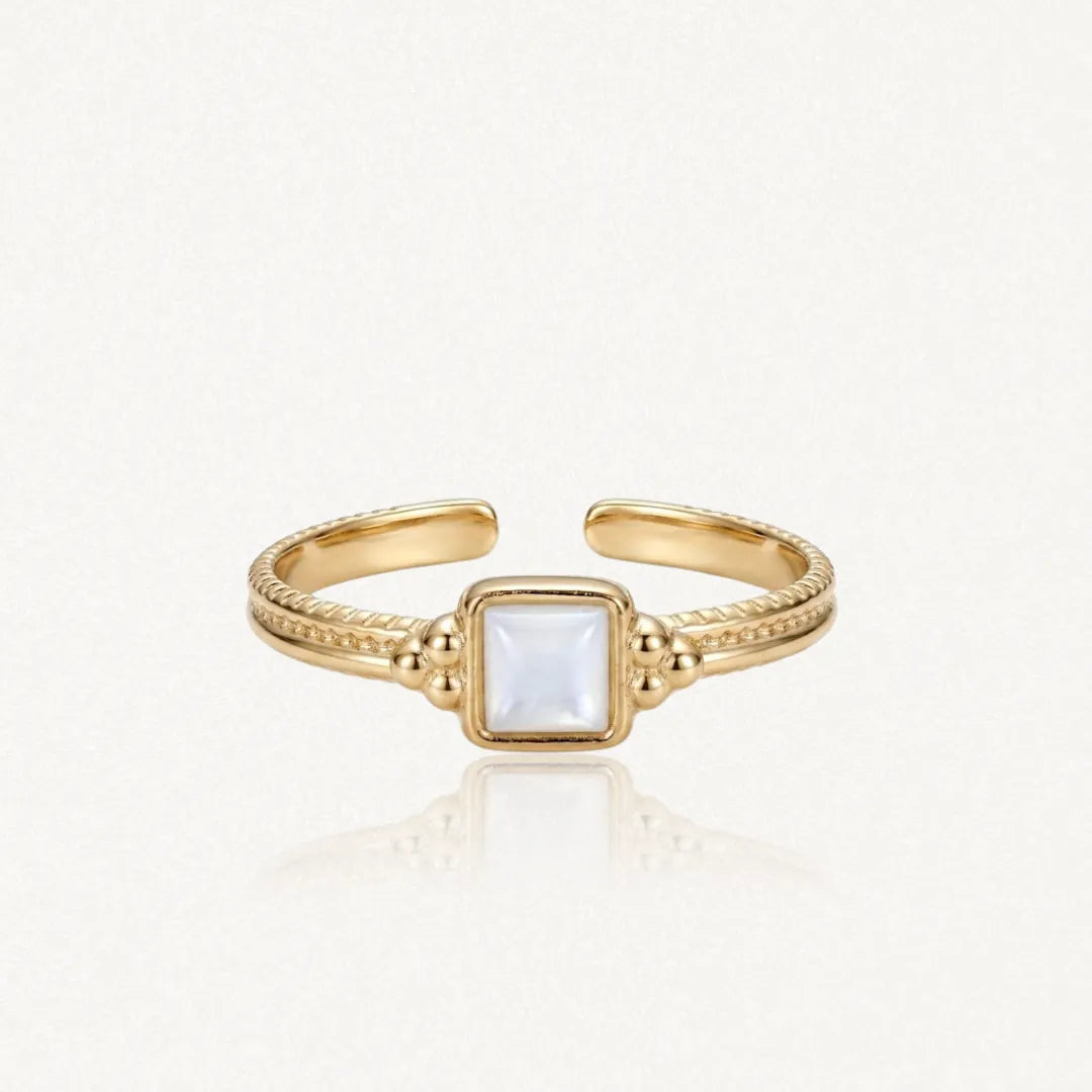 Bague ajustable en acier inoxydable doré, ornée d'une nacre carrée centrale et de détails perlés sur le corps.