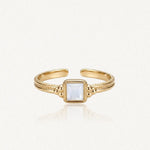 Bague ajustable en acier inoxydable doré, ornée d'une nacre carrée centrale et de détails perlés sur le corps.