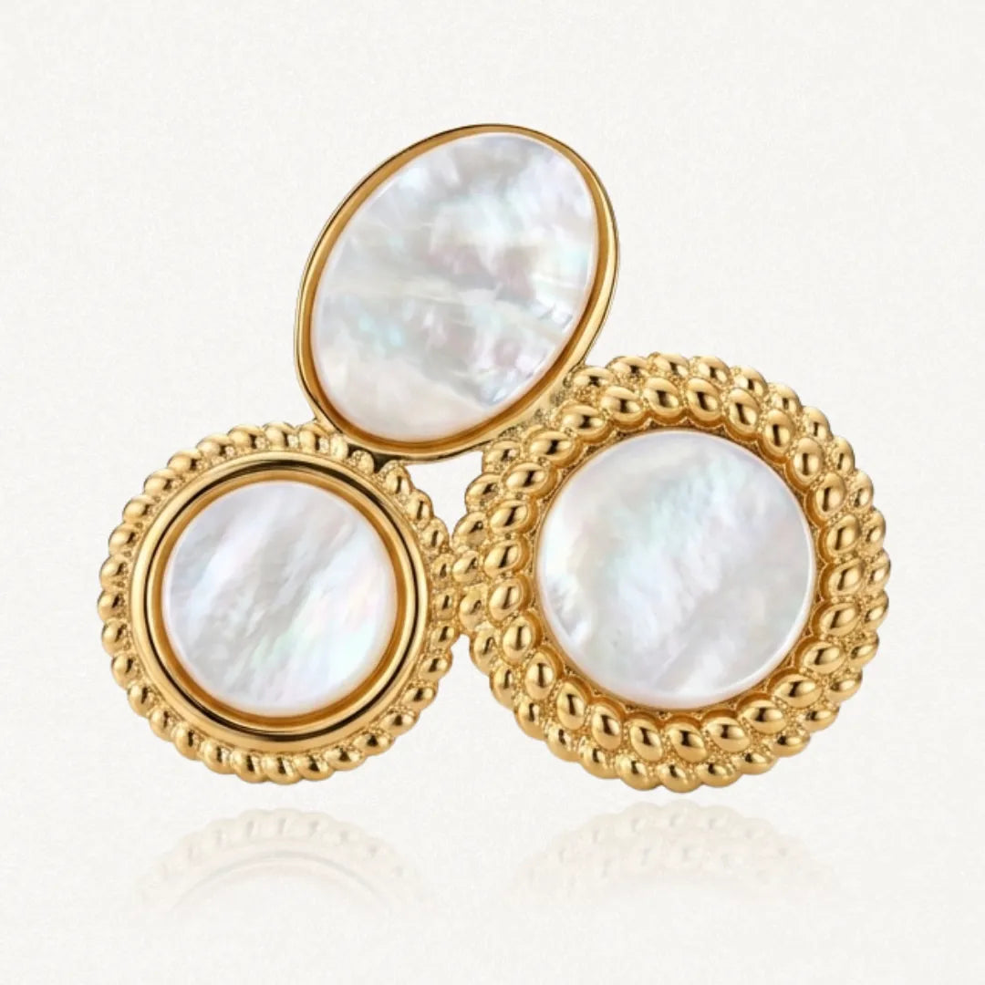 Bague en acier inoxydable doré avec trois pierres de résine effet nacre : une ovale et deux rondes, à bordures tressées.