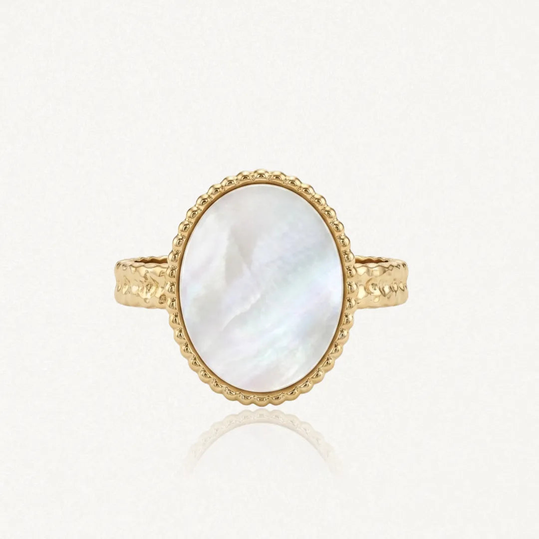 Bague en acier inoxydable doré, avec une nacre ovale irisée. Le serti est perlé et l'anneau martelé.