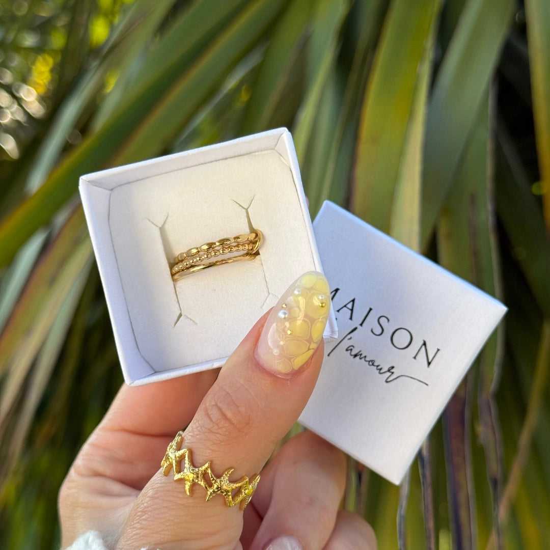 4 bagues dorées en acier inoxydable: bague zig-zag au doigt, 3 bagues fines (chaîne, perles, strass) en boîte Maison l'amour.