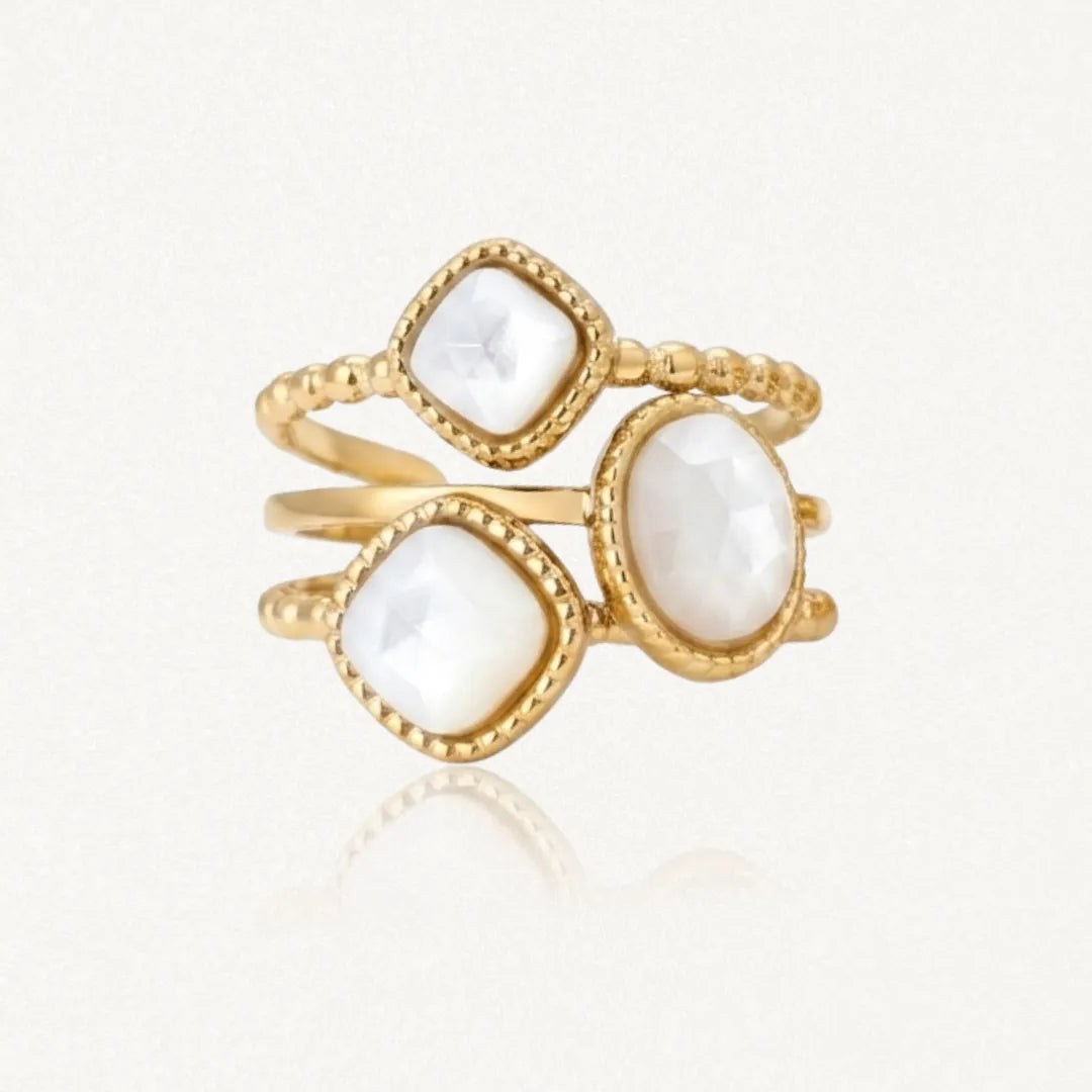 Bague dorée avec trois pierres de nacre à facettes, deux carrées et une ovale, sur des anneaux perlés.