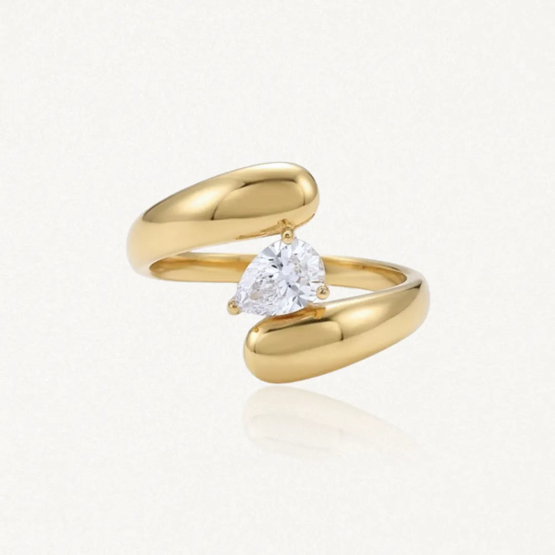 Bague ouverte en acier inoxydable doré, ornée d'un Zirconium taillé en poire et maintenu par trois griffes.