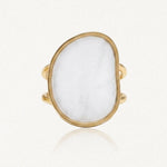 Bague dorée à double anneau, ornée d'un grand cabochon blanc opaque de forme irrégulière.