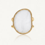 Bague dorée à double anneau, ornée d'un grand cabochon blanc opaque de forme irrégulière.