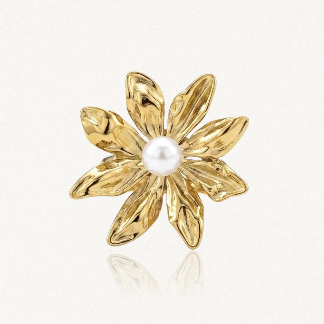 Bague en acier inoxydable doré, représentant une fleur à sept pétales texturés avec une perle blanche au centre.