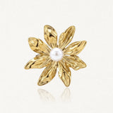 Bague en acier inoxydable doré, représentant une fleur à sept pétales texturés avec une perle blanche au centre.