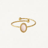 Bague ajustable en acier inoxydable doré texturé, avec nacre ovale rose pâle et deux billes aux extrémités.