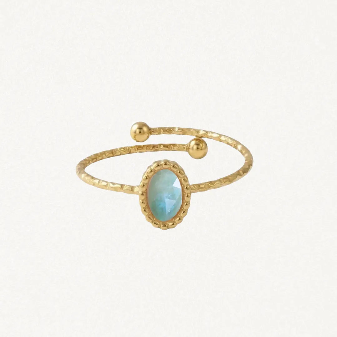Bague ouverte en acier inoxydable doré. L'anneau martelé est orné d'une pierre naturelle ovale bleu-vert clair facetée et de