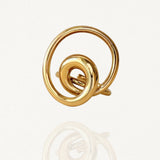 Bague dorée au design géométrique ajouré formant une spirale ou un cercle artistique sur fond blanc.
