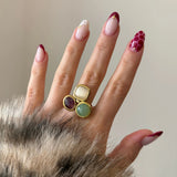 Bague originale multicolore portée sur une main manucurée, accessoirisant une tenue avec fausse fourrure.