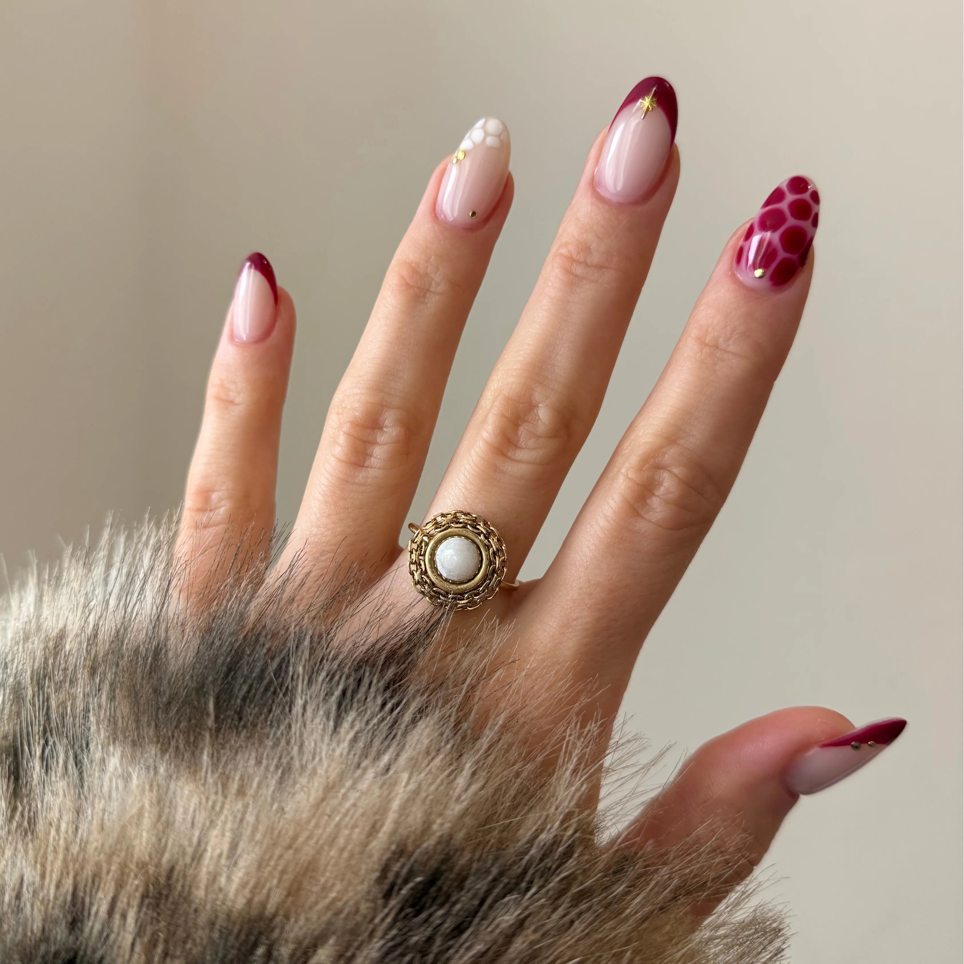 Bague tendance dorée avec large pierre blanche et contour travaillé, portée sur une main élégante.