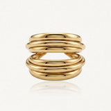 Bague en acier inoxydable doré, composée de six anneaux bombés parallèles séparés en son centre. Hauteur 1,80 cm.
