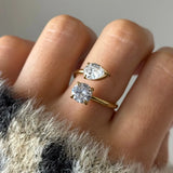 Bague toi et moi en acier inoxydable doré, avec un zirconium poire et un zirconium rond, portée au doigt.