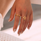 Bagues en acier inoxydable doré: bague coquillage sur le majeur, bague étoiles de mer sur l'index d'une femme.
