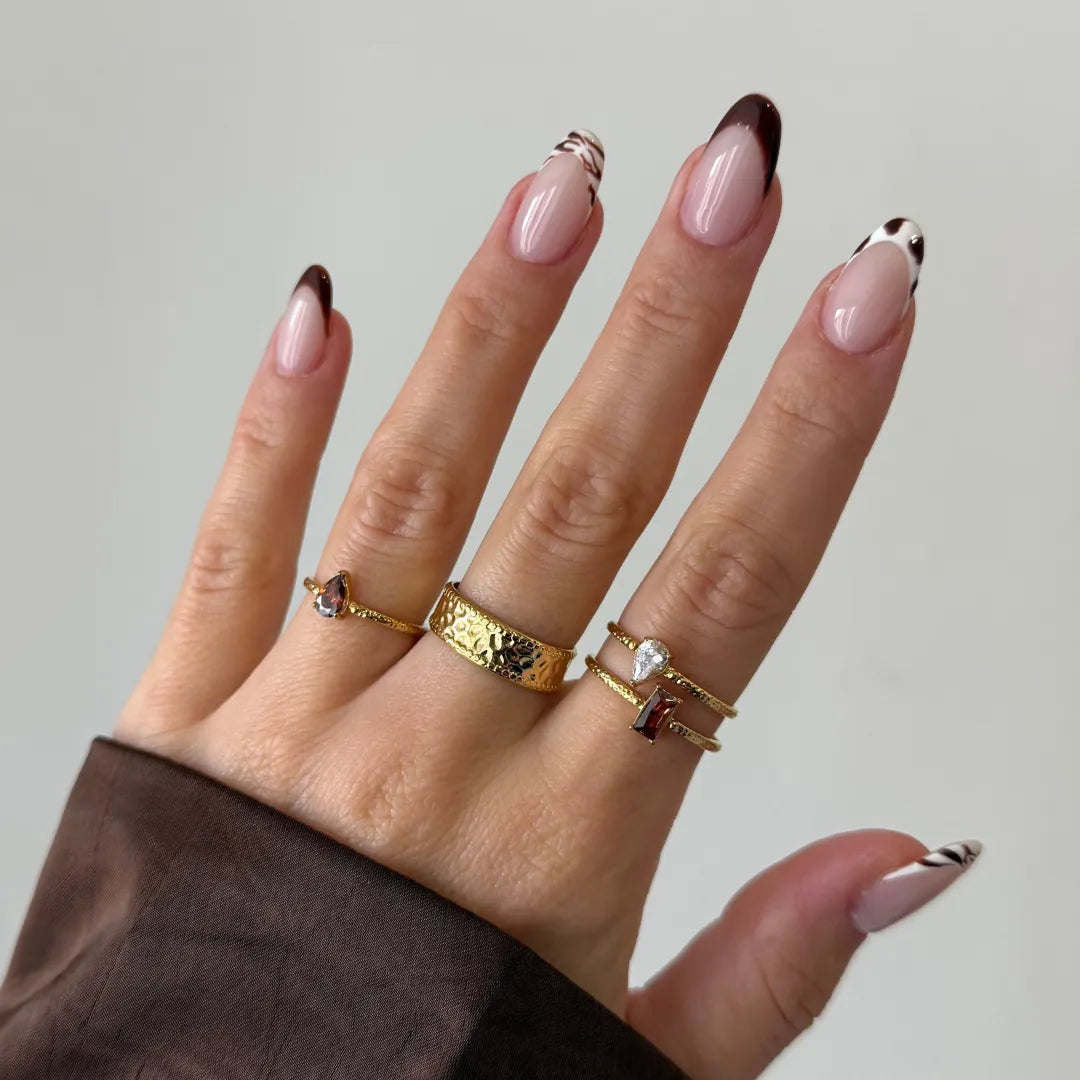 Bague ZELIE large en acier inoxydable doré avec une texture martelée portée sur le doigt majeur
