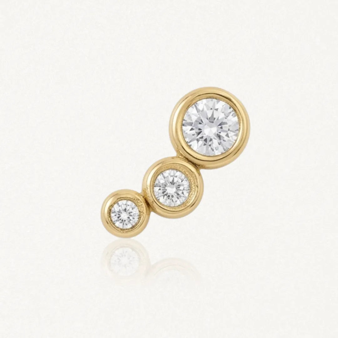 Piercing d'oreille en acier inoxydable doré, orné de trois zircons ronds gradués, sertis clos.