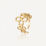 Boucle d'oreille dorée type manchette, ajourée, composée de fleurs à quatre pétales interconnectées.