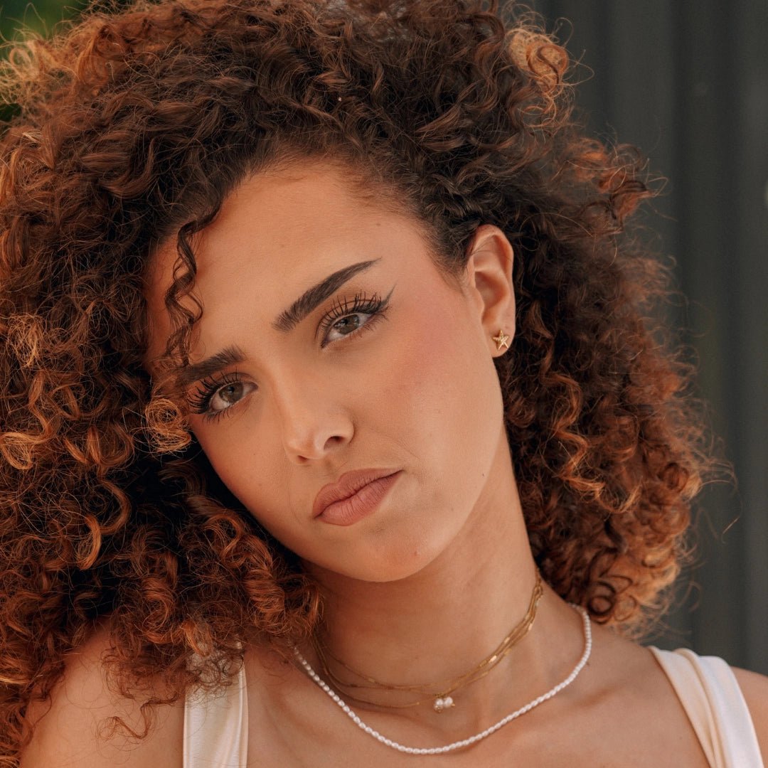 Boucles d'oreilles étoile en acier inoxydable doré, portées par une femme.