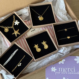 Boucles d'oreilles en acier inoxydable doré, design étoile de mer et coquillage, présentées sur fond noir.