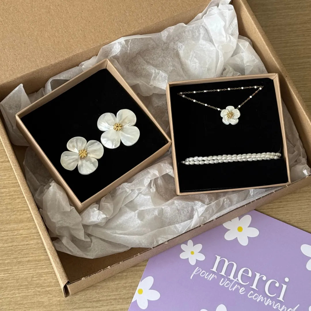 Boucles d'oreilles fleur en nacre et acier inoxydable doré, présentées avec un collier à perles et un bracelet perles dans