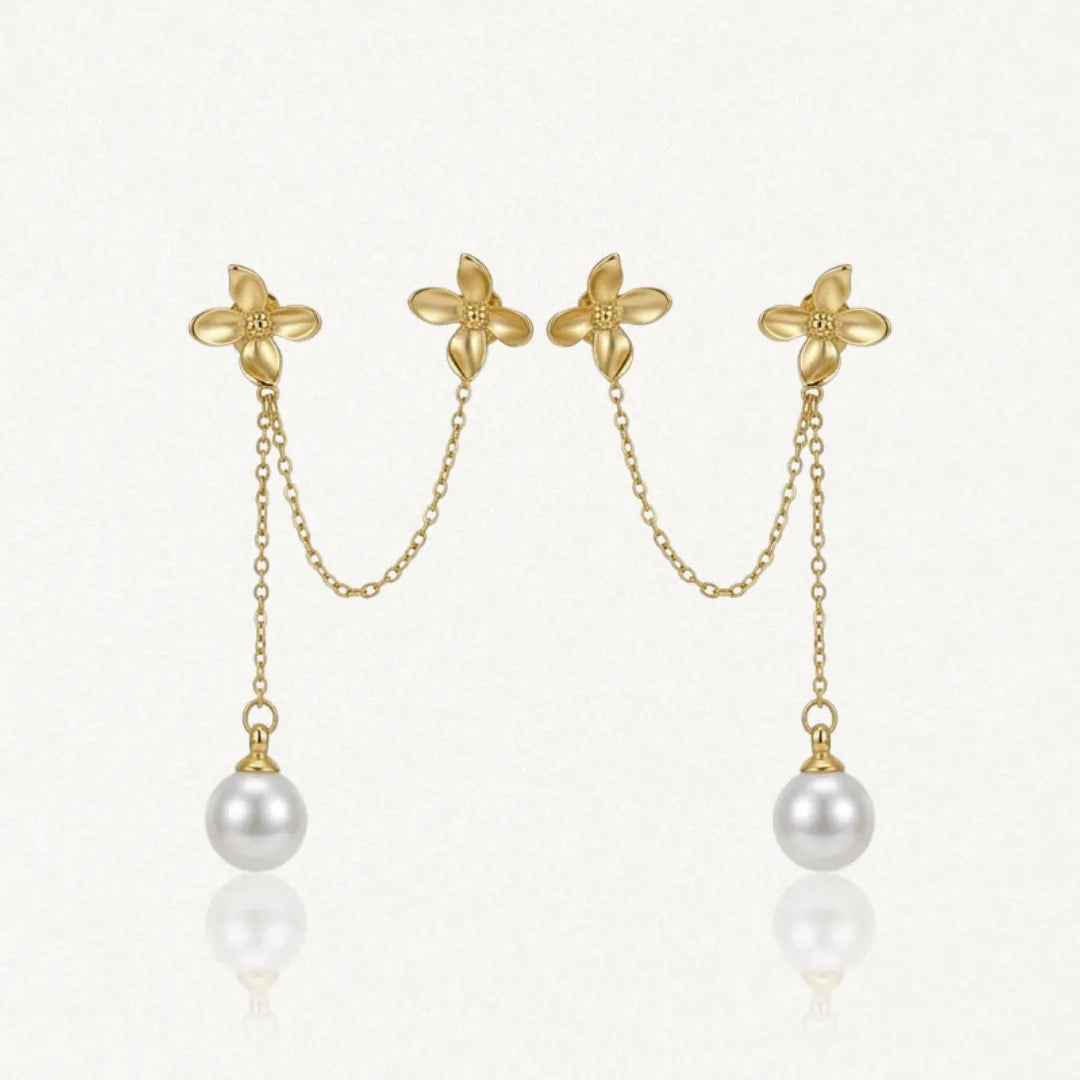 Deux boucles d'oreilles doubles en acier inoxydable doré, avec deux fleurs reliées par une chaîne, et une perle blanche
