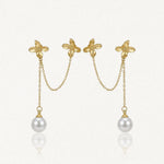 Deux boucles d'oreilles doubles en acier inoxydable doré, avec deux fleurs reliées par une chaîne, et une perle blanche