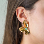 Boucle d'oreille fleurie en acier inoxydable doré texturé, centrée d'une pierre naturelle turquoise.