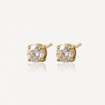 Paire de clous d'oreilles en or jaune avec pierres rondes incolores à facettes, sur fond clair et réfléchissant.