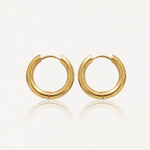 Paire de boucles d'oreilles créoles épaisses et dorées, brillantes, posées sur un fond clair avec reflets.