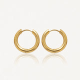 Paire de boucles d'oreilles créoles épaisses et dorées, brillantes, posées sur un fond clair avec reflets.