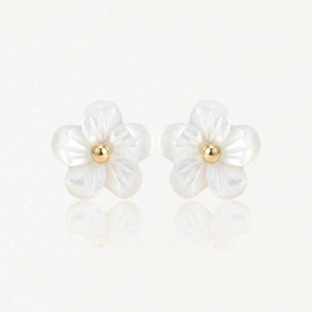 Paire de boucles d'oreilles à motif floral : deux fleurs à 5 pétales en nacre blanche irisée, avec un centre sphérique doré.