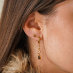 Boucle d'oreille créole pendante en acier inoxydable doré, avec une cascade de zircons champagne et marron, portée sur une