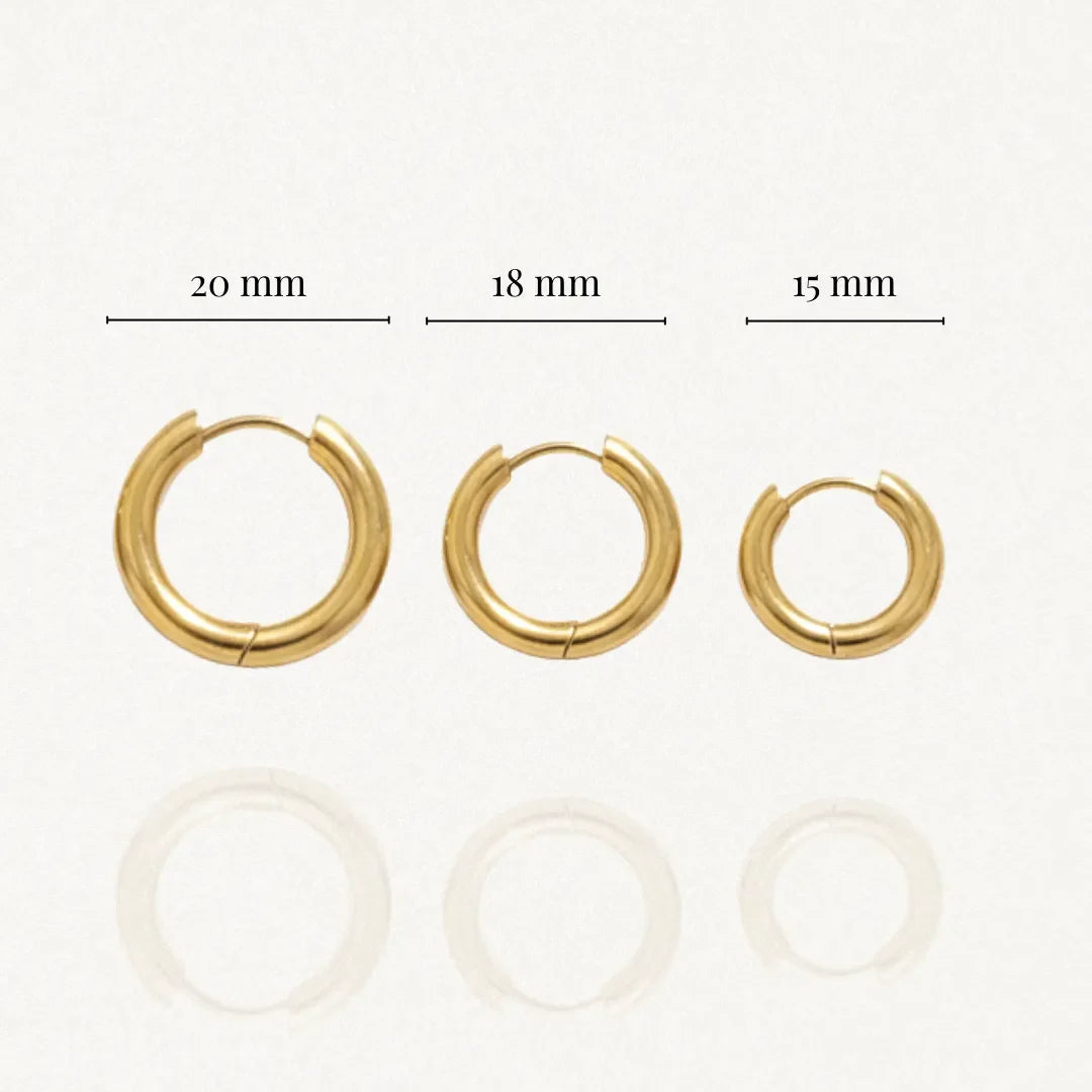 Trois boucles d'oreilles créoles dorées, diamètres 20 mm, 18 mm et 15 mm affichés, avec reflet léger.