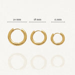 Trois boucles d'oreilles créoles dorées, diamètres 20 mm, 18 mm et 15 mm affichés, avec reflet léger.