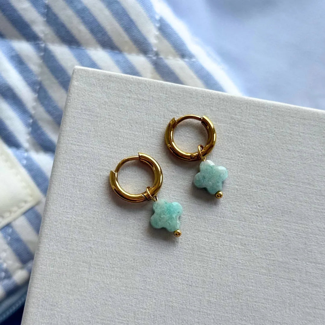 Paire de boucles d'oreilles créoles acier inoxydable doré, pendentifs trèfles en pierre naturelle bleu-vert et bille dorée.