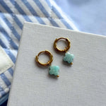 Paire de boucles d'oreilles créoles acier inoxydable doré, pendentifs trèfles en pierre naturelle bleu-vert et bille dorée.