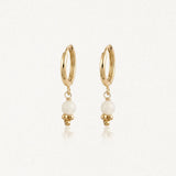 Deux boucles d'oreilles créoles en acier inoxydable doré, avec une bille ronde blanche et trois petites billes dorées en