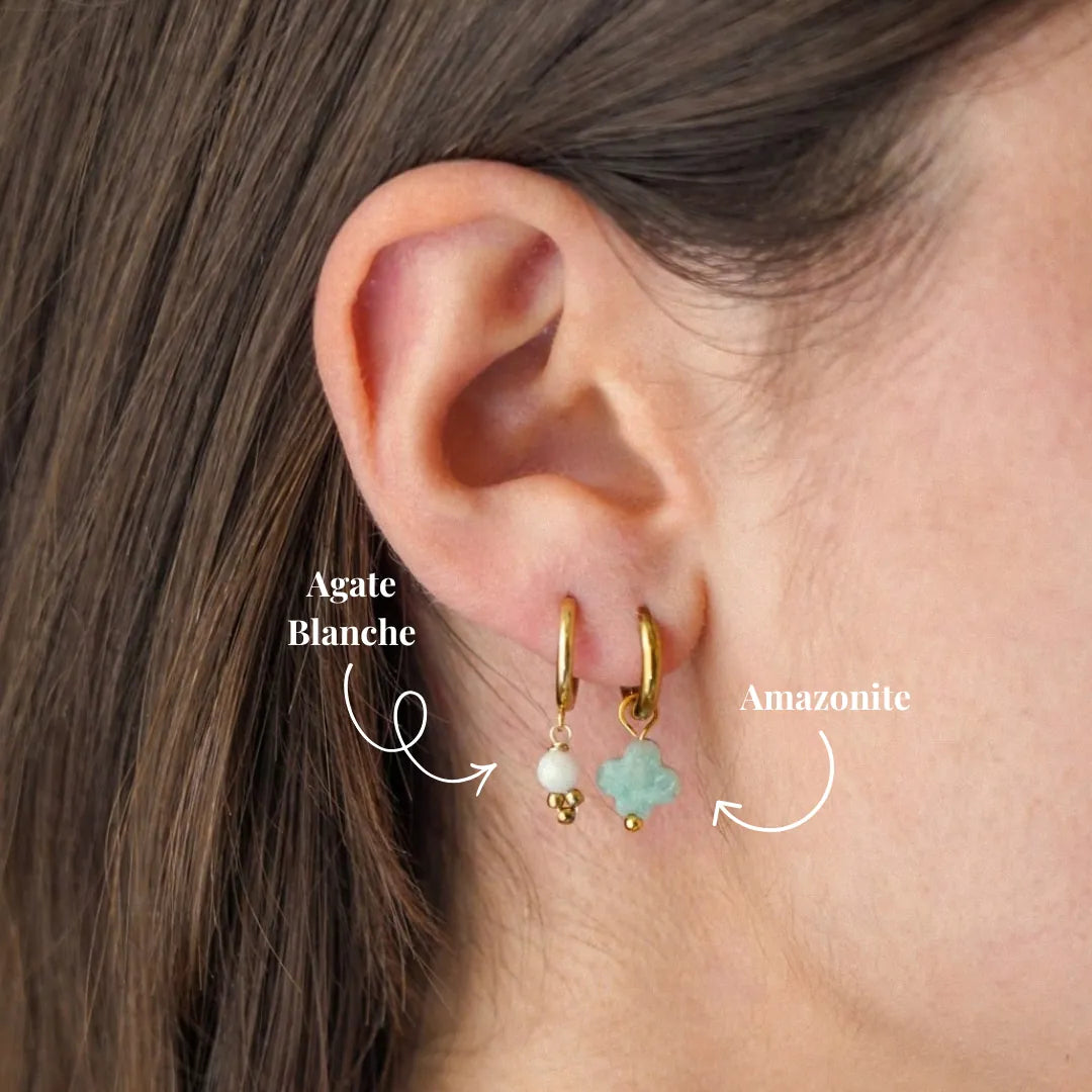 Deux boucles d'oreilles créoles en acier inoxydable doré sur une oreille. L'une avec agate blanche, l'autre avec amazonite