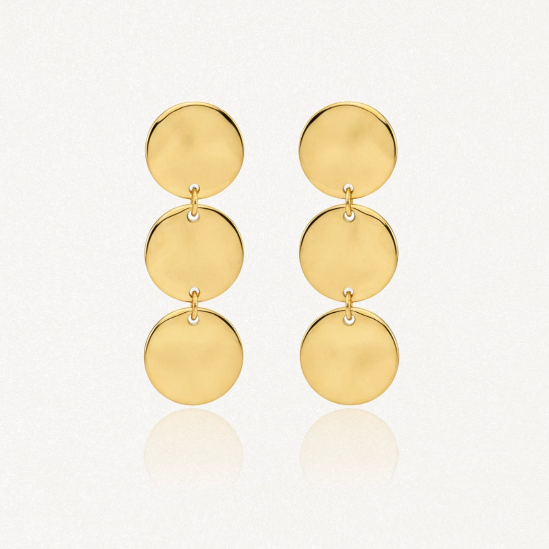 Deux boucles d'oreilles pendantes dorées, chacune composée de trois disques circulaires brillants et plats, reliés