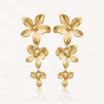 Paire de boucles d'oreilles dorées pendantes, composées de trois fleurs stylisées en relief de taille décroissante.