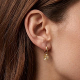 Boucle d'oreille mini créole en acier inoxydable dore avec un pendentif fleur texturé et un strass zirconium central sur une
