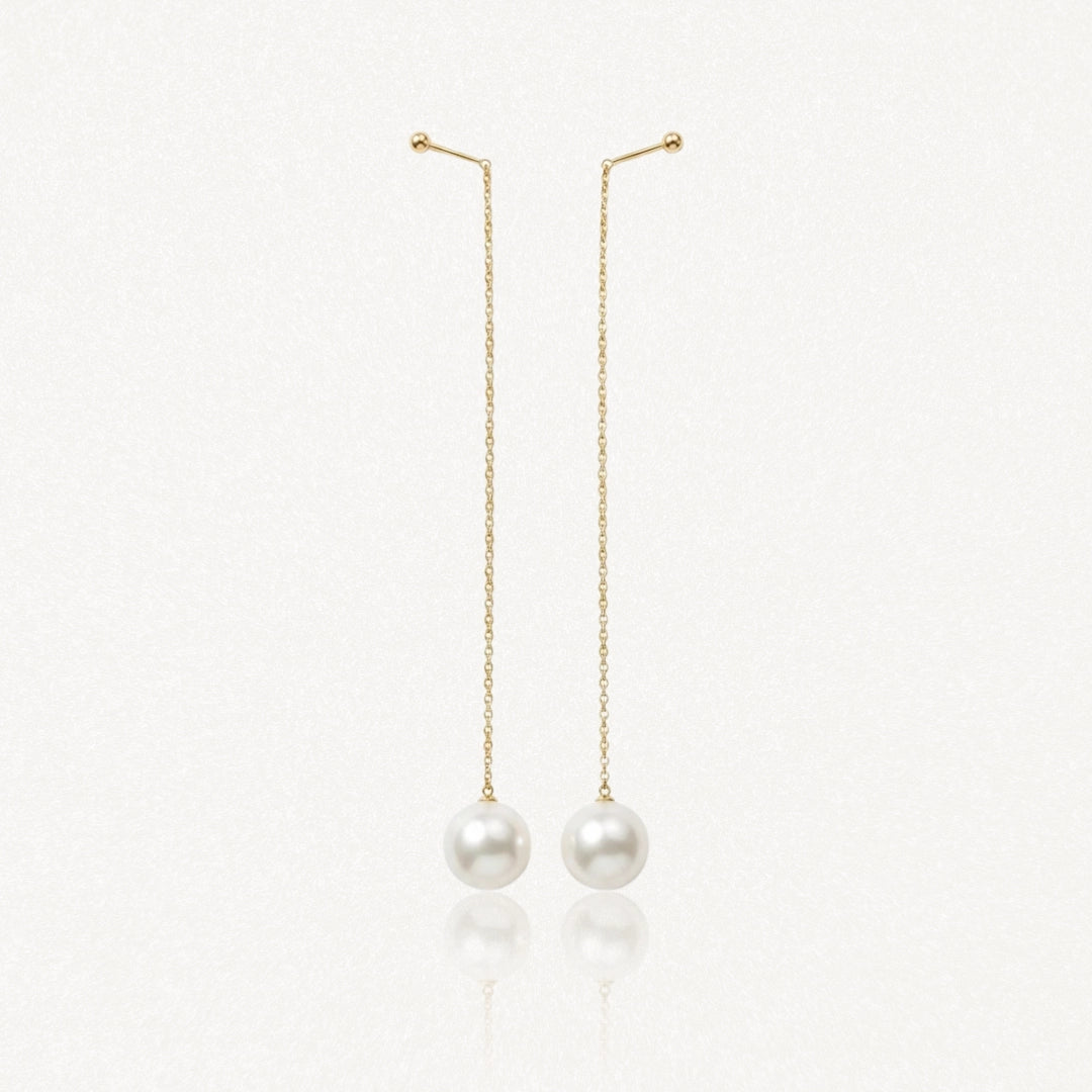 Paire de boucles d'oreilles pendantes à chaîne dorée avec fixation à boule et perle blanche ronde.