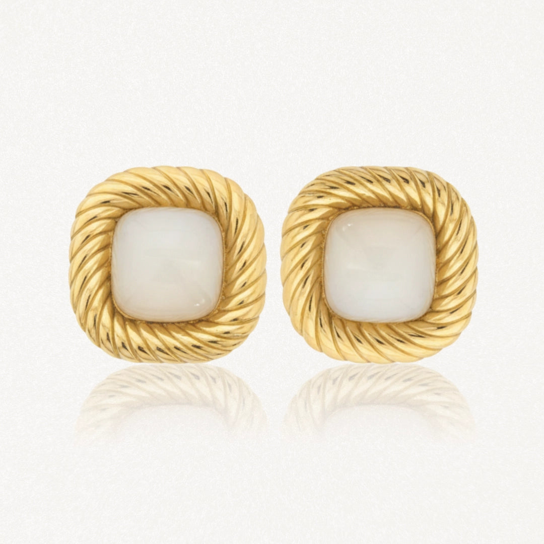 Paire de boucles d'oreilles carrées dorées, à bord torsadé, avec une pierre centrale blanche nacrée.
